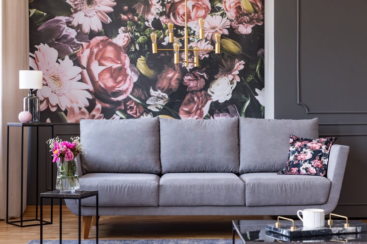 Living room with grey sofa in front of a bold floral wallpaper print