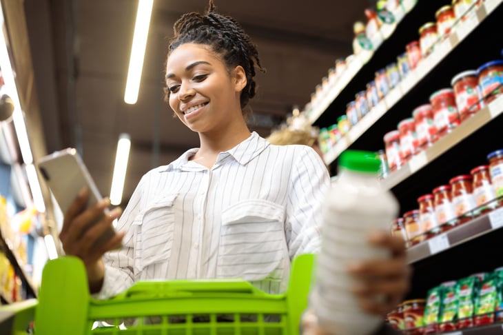 Woman looking at her phone while shopping in the grocery store