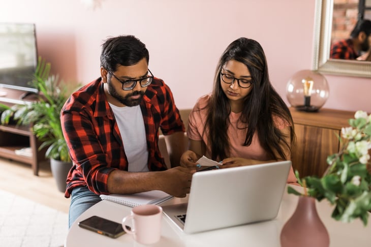 Couple doing taxes using a notebook, receipts and a laptop