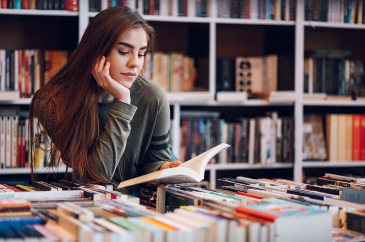 Young woman looking at a used book in a book store.