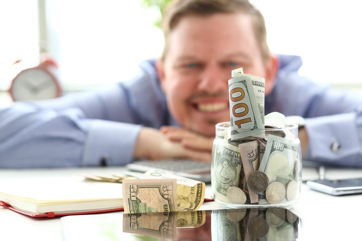 Man looking at a jar full of cash