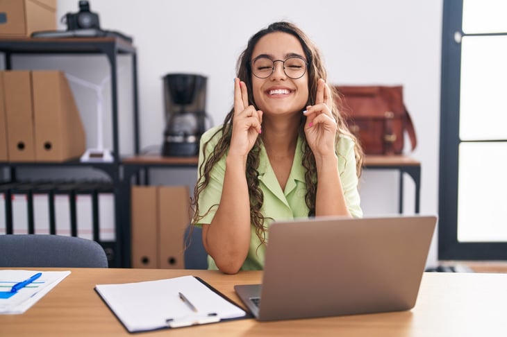 woman with fingers crossed in front of computer