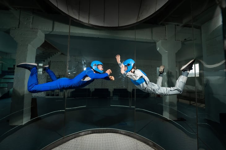 A man and a woman enjoy indoor skydiving together in a wind tunnel.