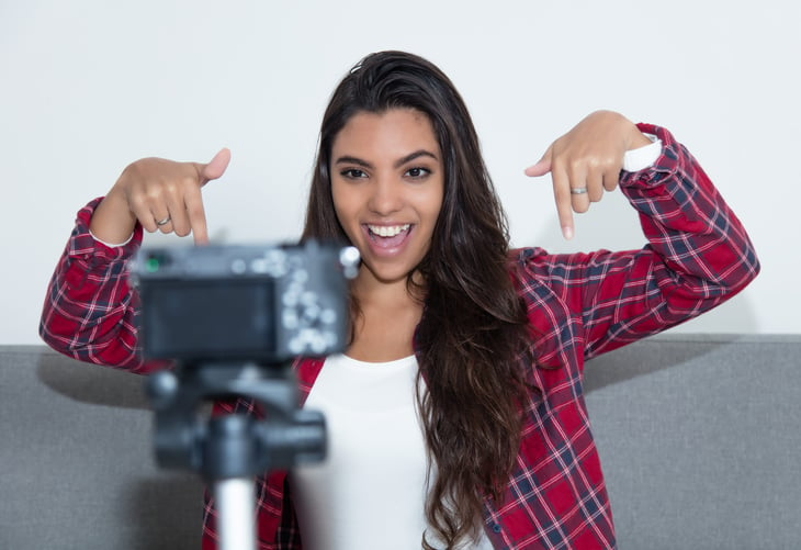 Young woman influencer recording video blog with camera at home