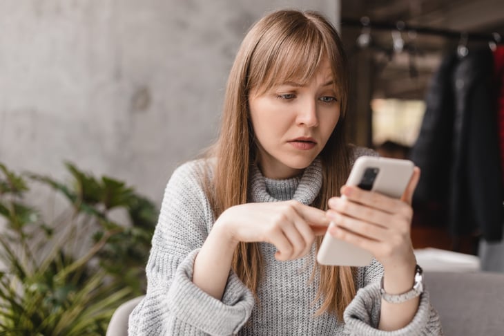 Frustrated woman looking at smartphone with a bad signal or suspicious message