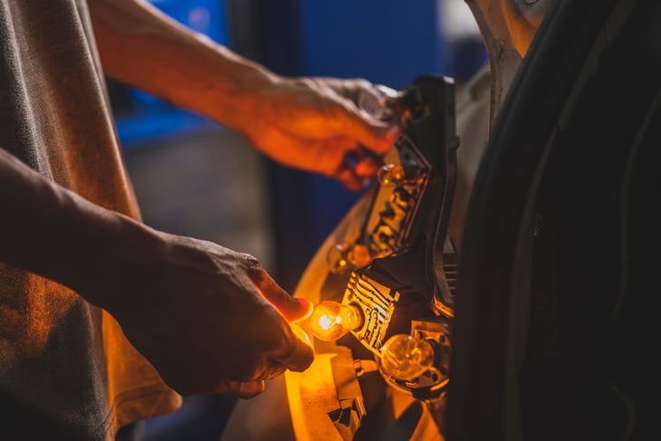 Hands changing a taillight bulb or rear turn signal light bulb