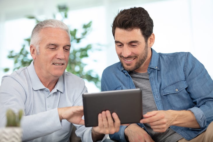 Older man giving advice to younger man and using a tablet