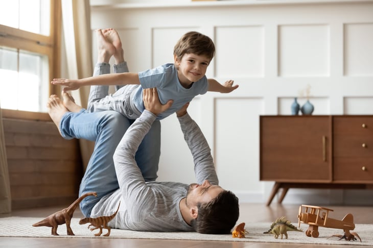 father lying on the floor at home playing with young son