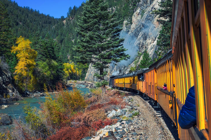 Historic steam engine train travels from Durango to Silverton through the San Juan Mountains along the Animas River in Colorado, USA.
