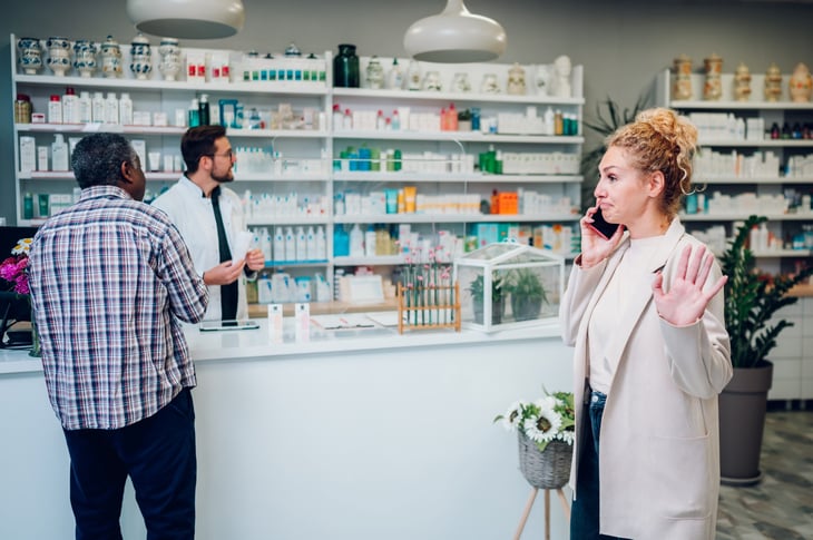 Woman in line at the pharmacy, talking on her smartphone.