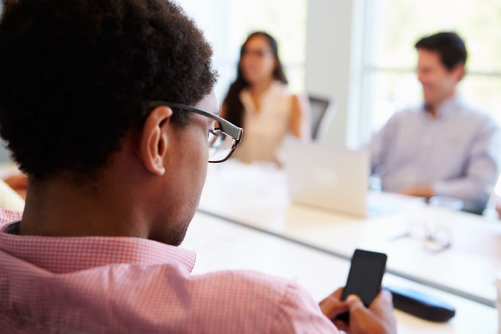A person uses their phone during a business meeting.