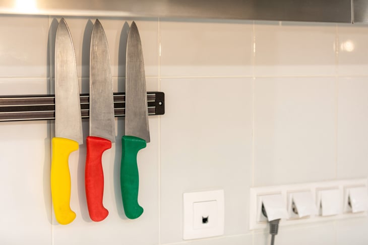 Set of three multi-colored kitchen knives on a magnetic strip