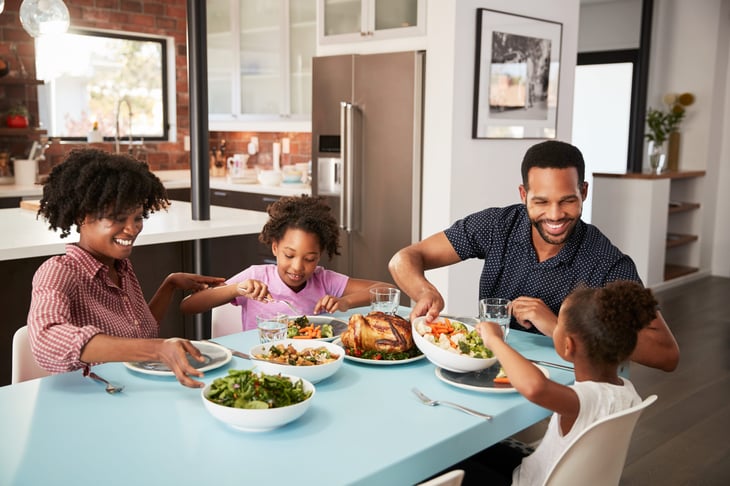 A family sits a table, eating dinner