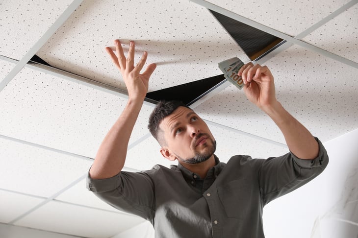 Man hiding cash money in the ceiling