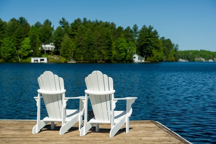 Adirondack chairs on a dock on a lake
