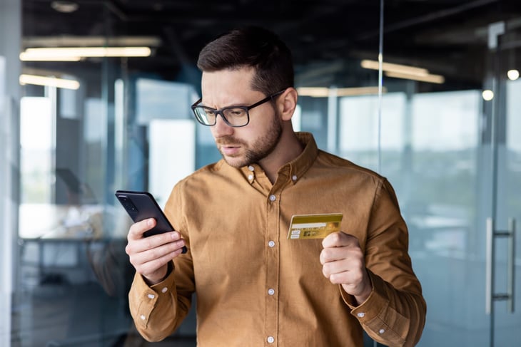 Worried consumer with credit card looking at his phone