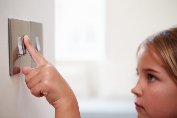 Young girl turning off a light switch