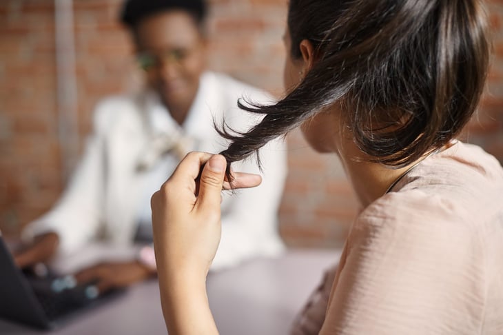 Woman nervously playing with or fidgeting with her hair in an interview.