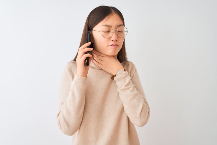 Young woman on the phone clearing her throat.