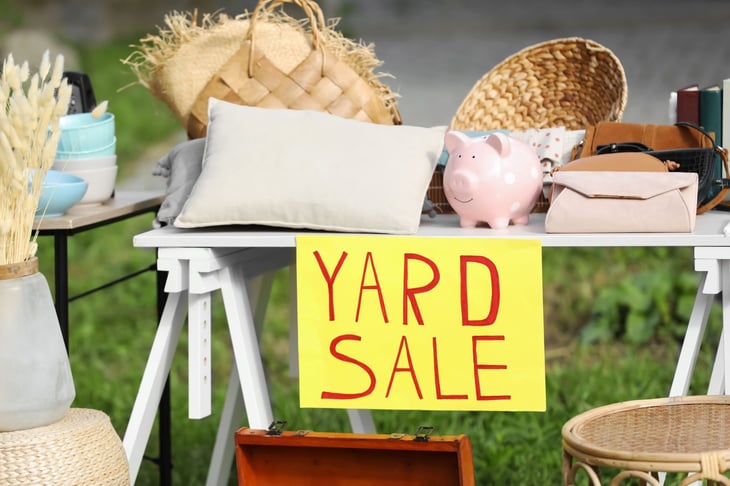 Table with yard sale sign and different items for sale.