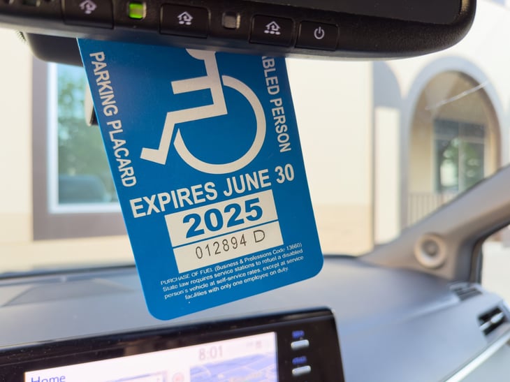 ADA Disabled Person placard hung on a rear view mirror of a car.
