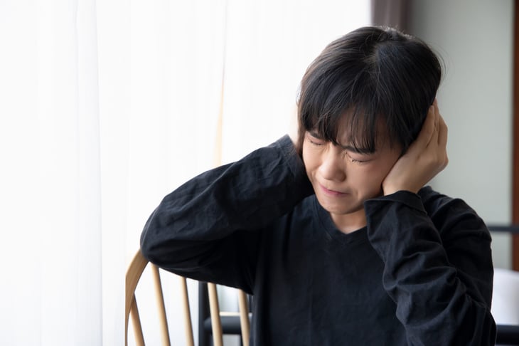 Woman covering her ears in noisy home