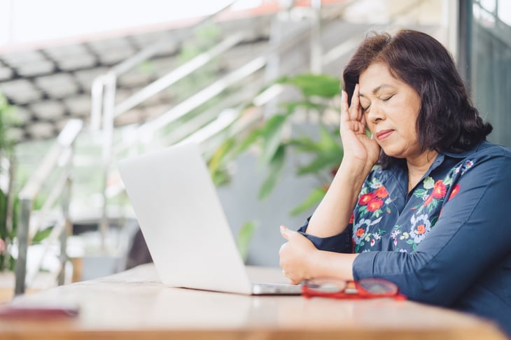 Stressed businesswoman using laptop with a headache or feeling tired
