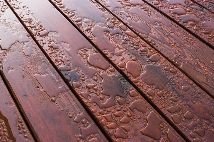 Wet puddle or pooled water on a patio wooden deck outside
