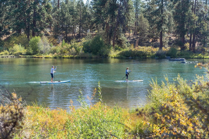 Couple paddleboarding on the river in Bend, Oregon