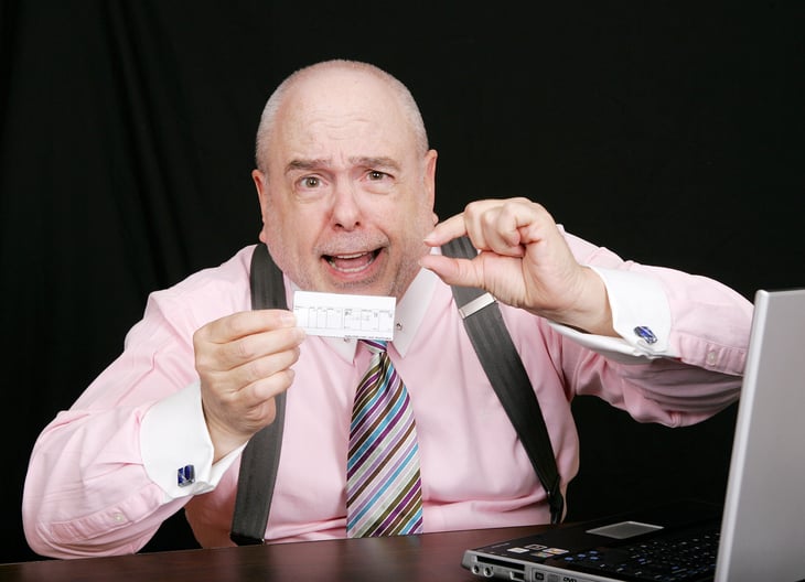 Worker or boss emphasizing a tiny paycheck or little money sitting at a laptop on a desk