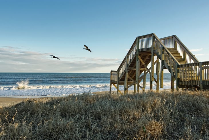 Birds flying over Pier Topsail Island Beach in Jacksonville, North Carolina.