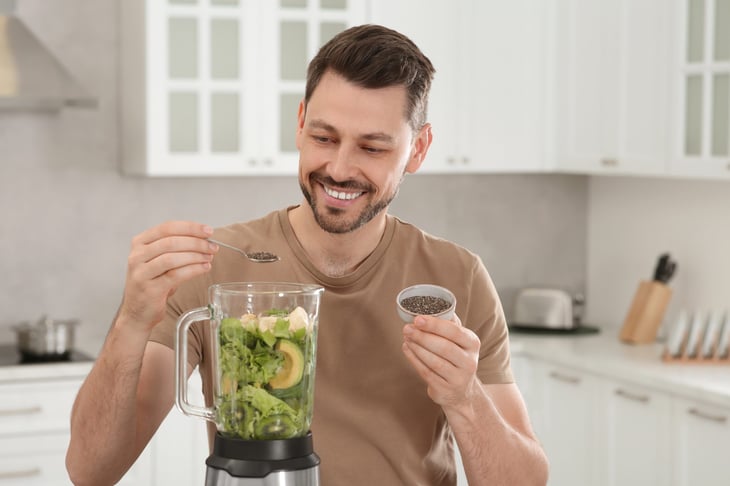 Man adding chia seeds for green smoothie