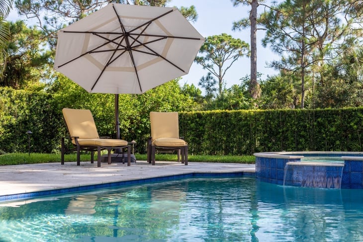 A backyard pool with chairs and an umbrella. 