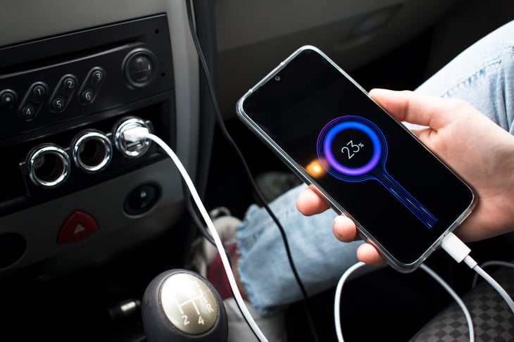 A phone plugged into a car's console and charging