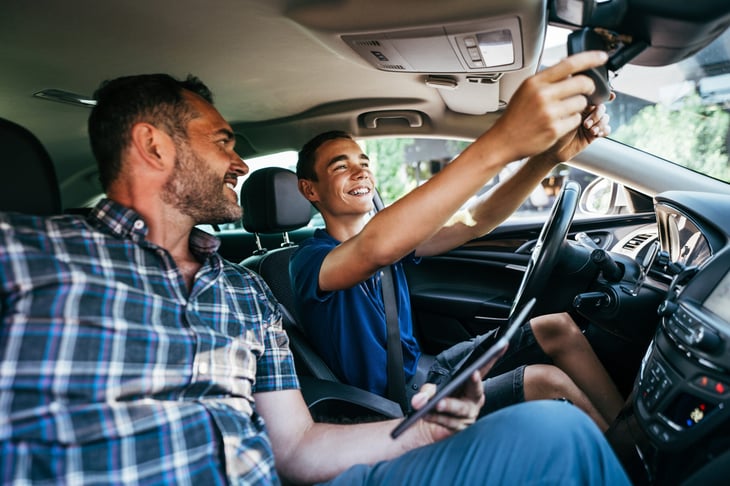 Man instructing a teen boy on how to drive