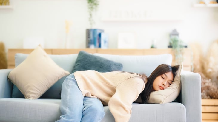 Tired woman sleeping awkwardly on the couch passed out asleep from exhaustion