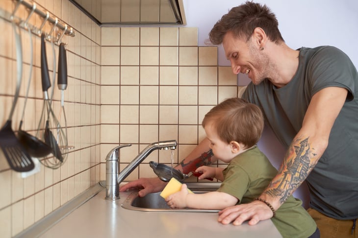 Young child helps dad with doing the dishes