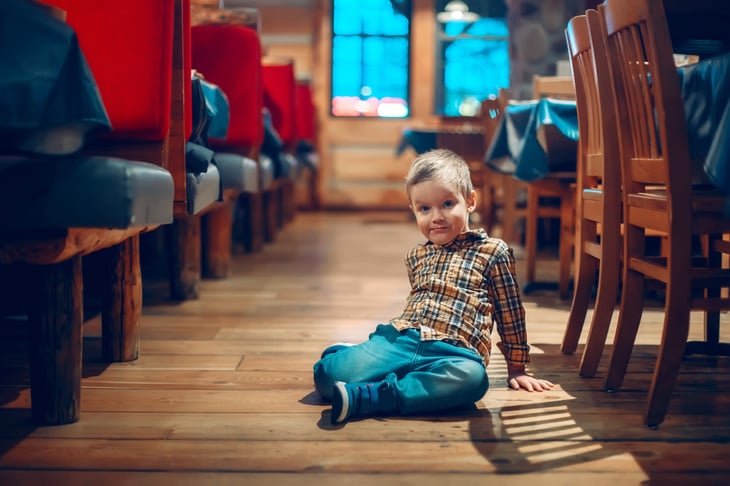 Toddler sitting on the floor of a restaurant. 