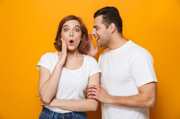 Excited man tells woman a surprising secret.