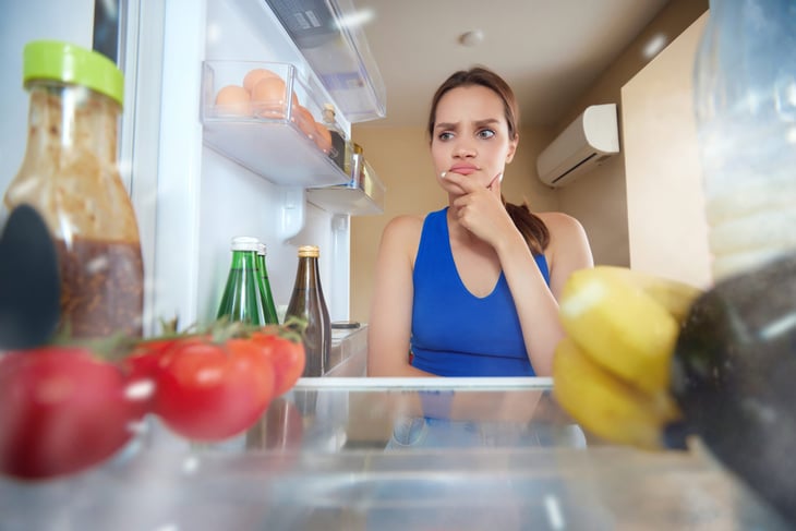 Young woman opening fridge, looking inside