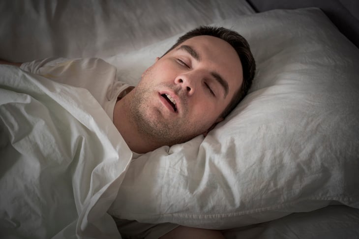Man in bed asleep and snoring.