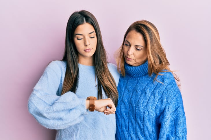 Mother and daughter looking down at a watch.
