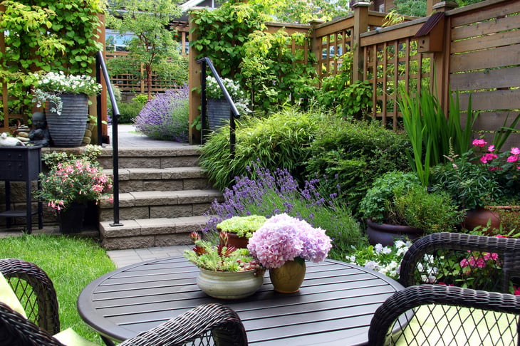 Private garden or backyard patio with outdoor seating and fencing with part of the fence as a lattice
