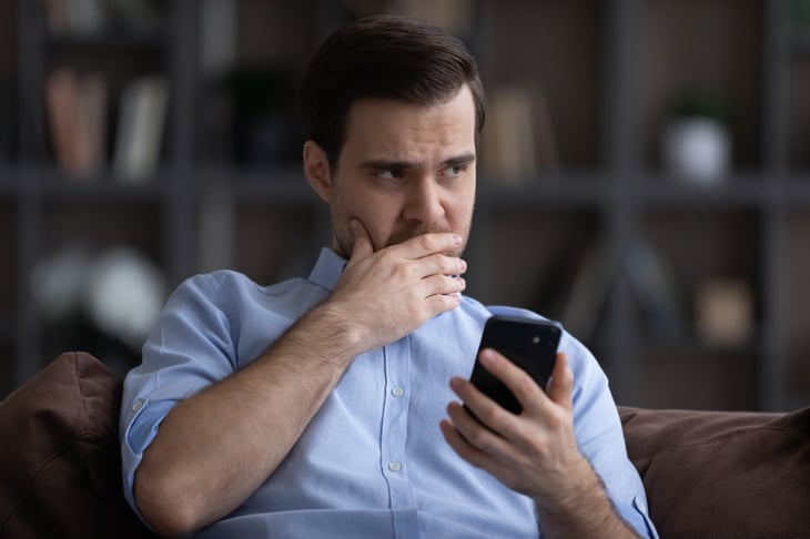 Man worried while holding cell phone.