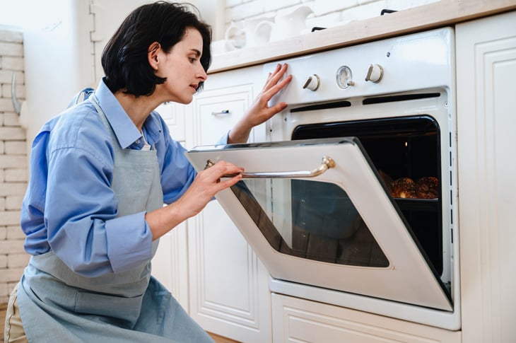 Woman opening oven door