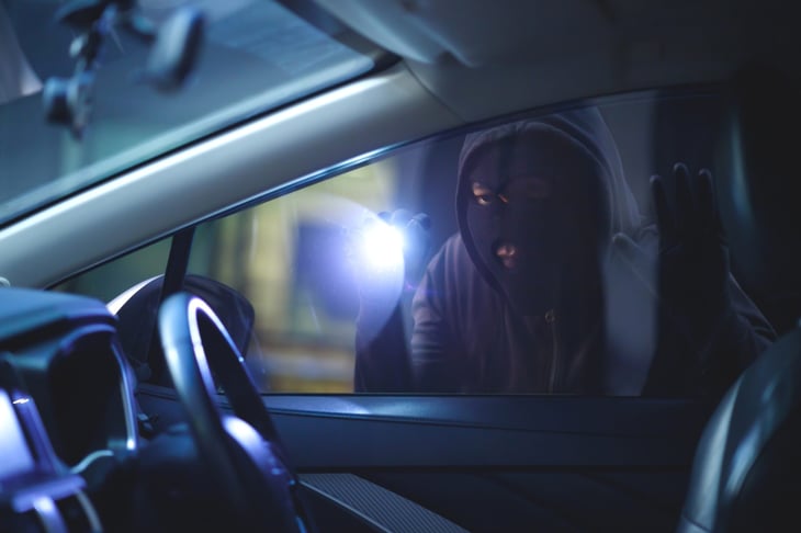 Thief looking at a car to steal.