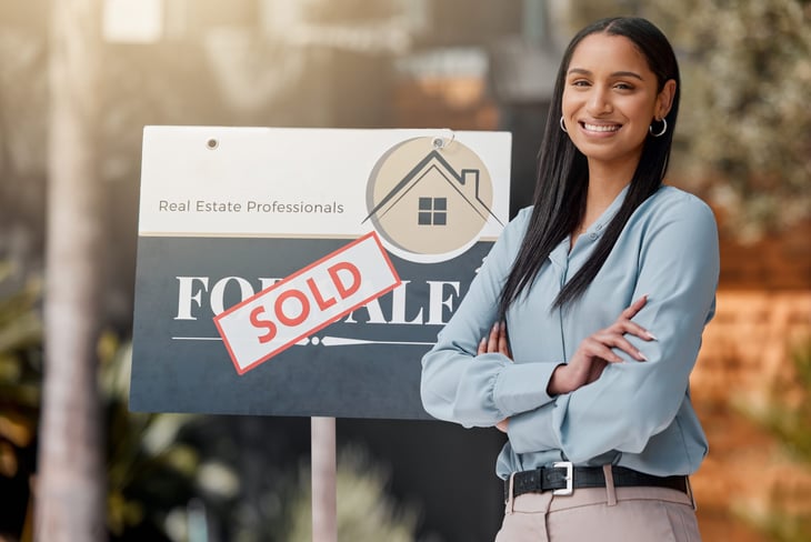 Real estate agent in front of "sold" sign