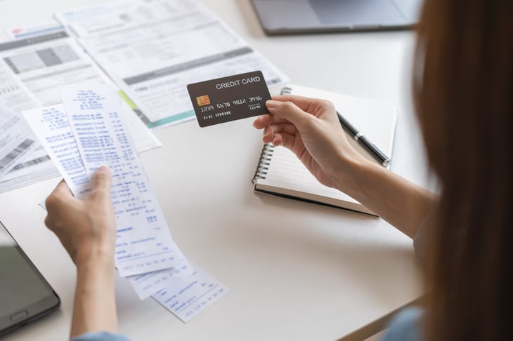 Woman holding credit card and bills, worried about debt