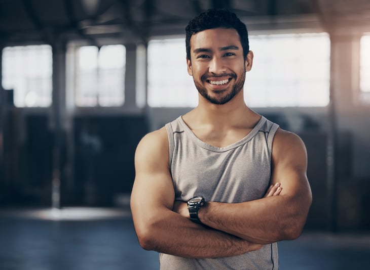 Health coach or personal trainer with crossed arms in a gym