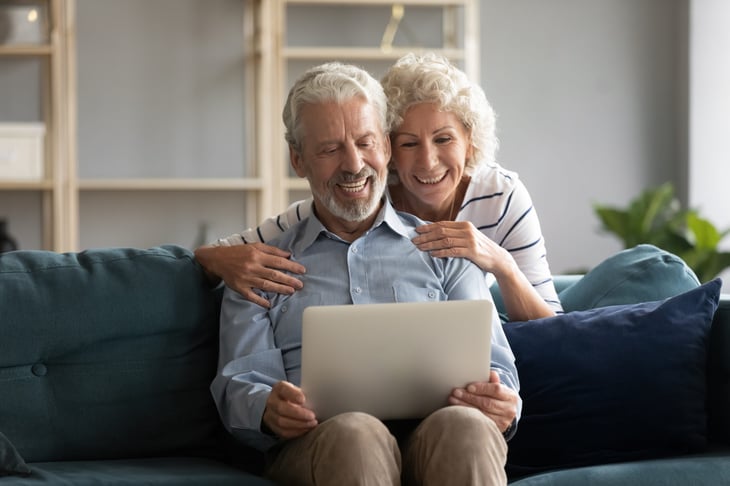 Smiling older couple looking at their laptop on the couch.